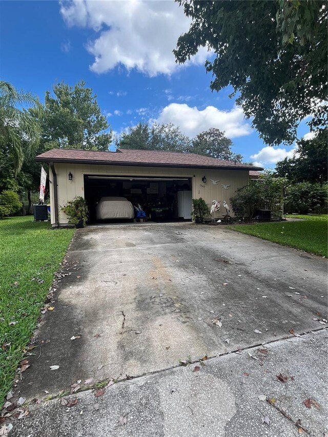 view of side of property with a garage, a lawn, and central AC unit