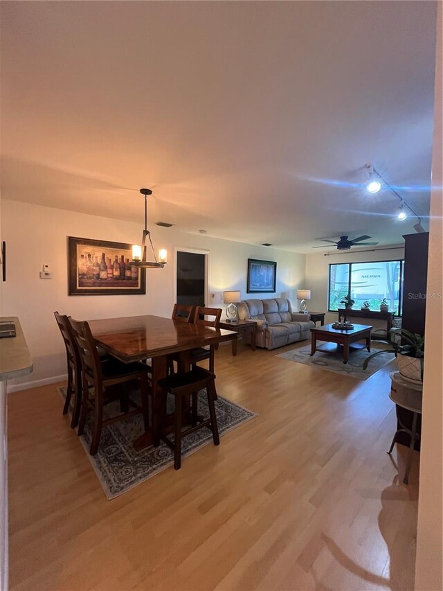 dining area with wood-type flooring and ceiling fan with notable chandelier