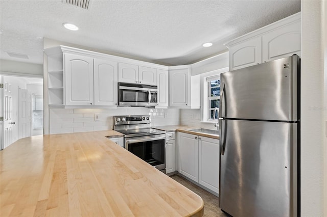 kitchen featuring white cabinets, appliances with stainless steel finishes, and tasteful backsplash