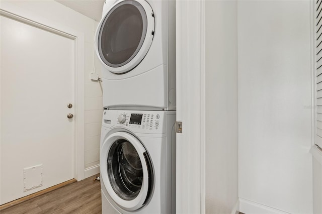 laundry room with stacked washer and clothes dryer and light hardwood / wood-style floors