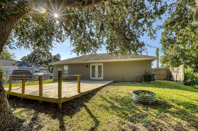 rear view of house with french doors, a wooden deck, a lawn, and central air condition unit