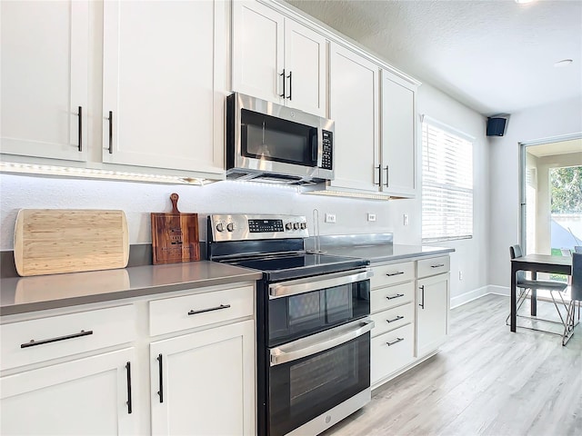 kitchen with light hardwood / wood-style floors, white cabinetry, a textured ceiling, and appliances with stainless steel finishes