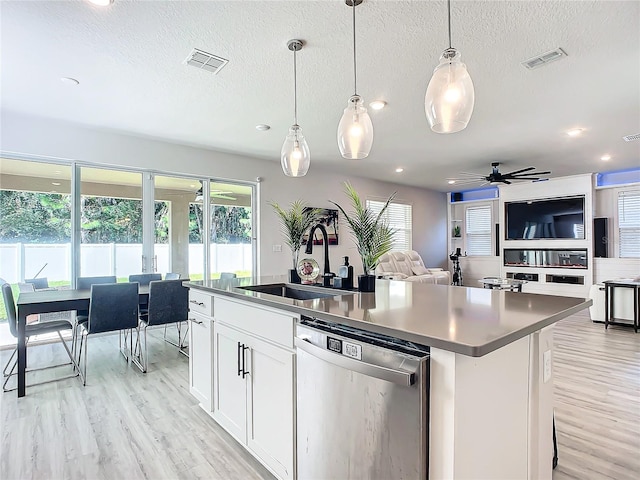 kitchen with ceiling fan, dishwasher, sink, a kitchen island with sink, and white cabinets