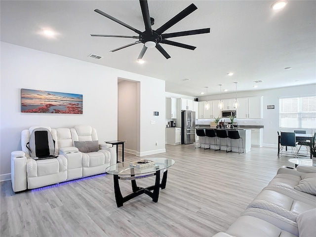 living room with light hardwood / wood-style flooring and ceiling fan