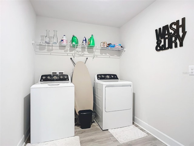 clothes washing area featuring light wood-type flooring and washer and clothes dryer