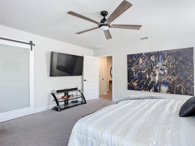 carpeted bedroom with a barn door, ceiling fan, and a textured ceiling