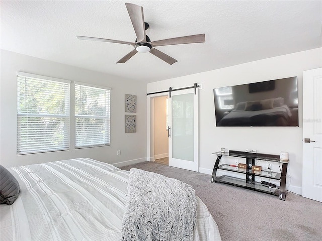 carpeted bedroom featuring ceiling fan, a barn door, and a textured ceiling