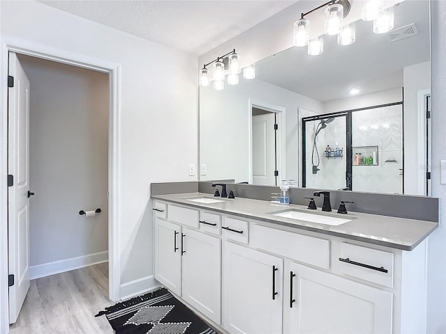 bathroom with hardwood / wood-style floors, vanity, a textured ceiling, and walk in shower