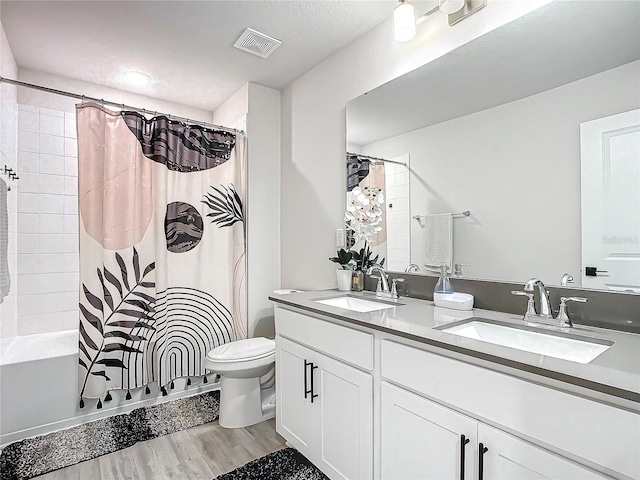 full bathroom featuring hardwood / wood-style floors, vanity, shower / tub combo, and toilet