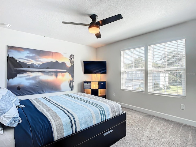 bedroom with ceiling fan, light colored carpet, and a textured ceiling