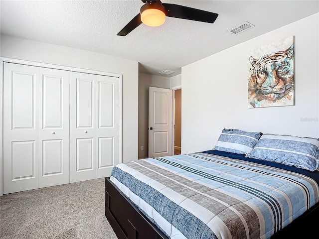 carpeted bedroom with ceiling fan, a closet, and a textured ceiling