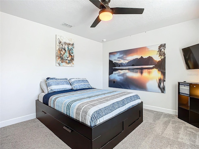 carpeted bedroom featuring ceiling fan and a textured ceiling