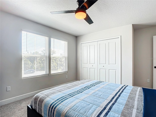 bedroom with ceiling fan, a closet, carpet floors, and a textured ceiling