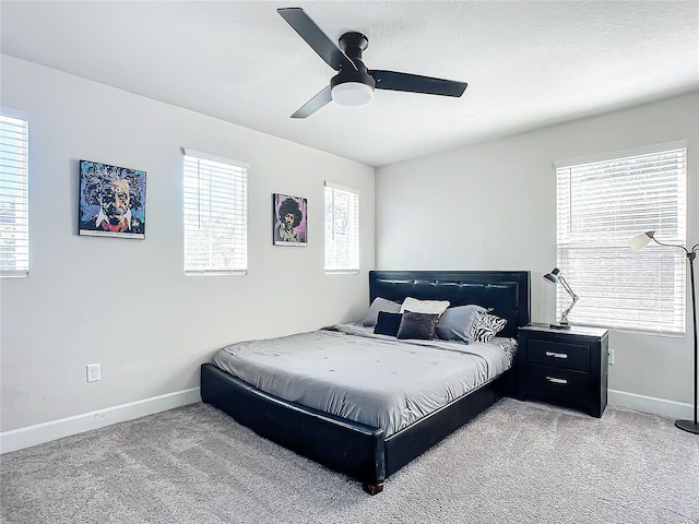 bedroom featuring ceiling fan, light carpet, and multiple windows