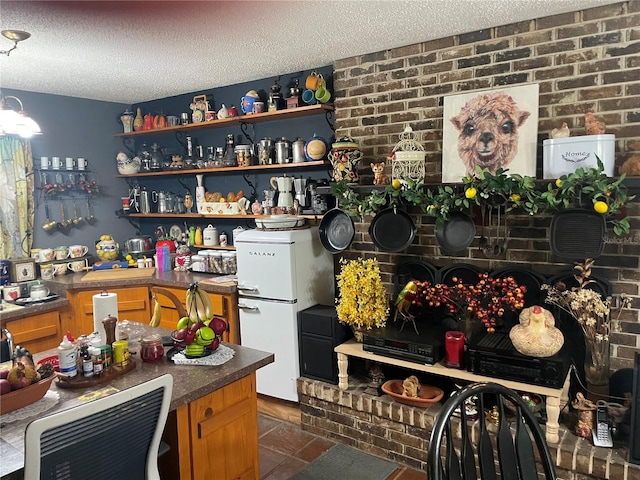 interior space featuring a textured ceiling, brick wall, and white refrigerator