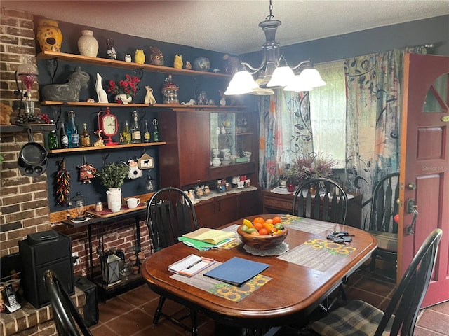 dining space featuring a textured ceiling, brick wall, tile patterned flooring, and a notable chandelier