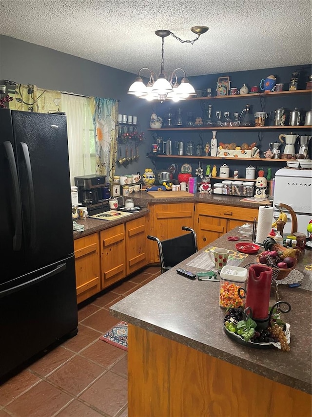 kitchen with black fridge, a textured ceiling, dark tile patterned floors, decorative light fixtures, and a chandelier