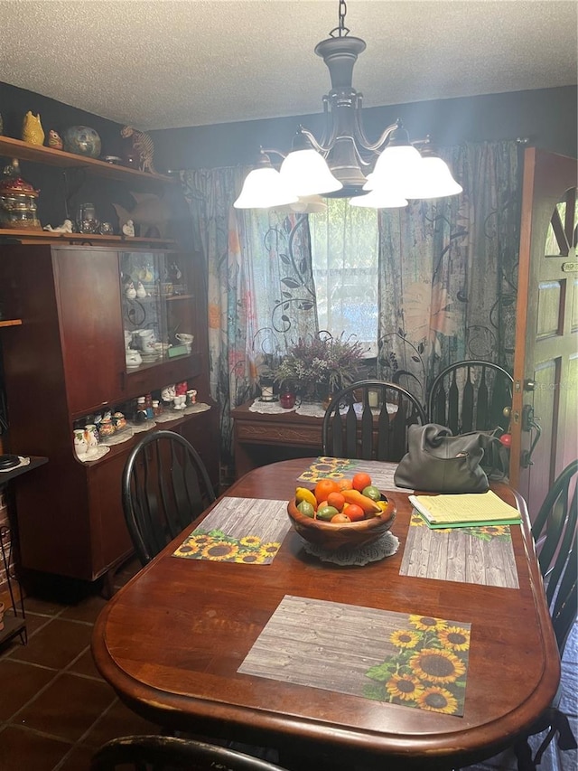 dining space with an inviting chandelier, a textured ceiling, and dark tile patterned floors