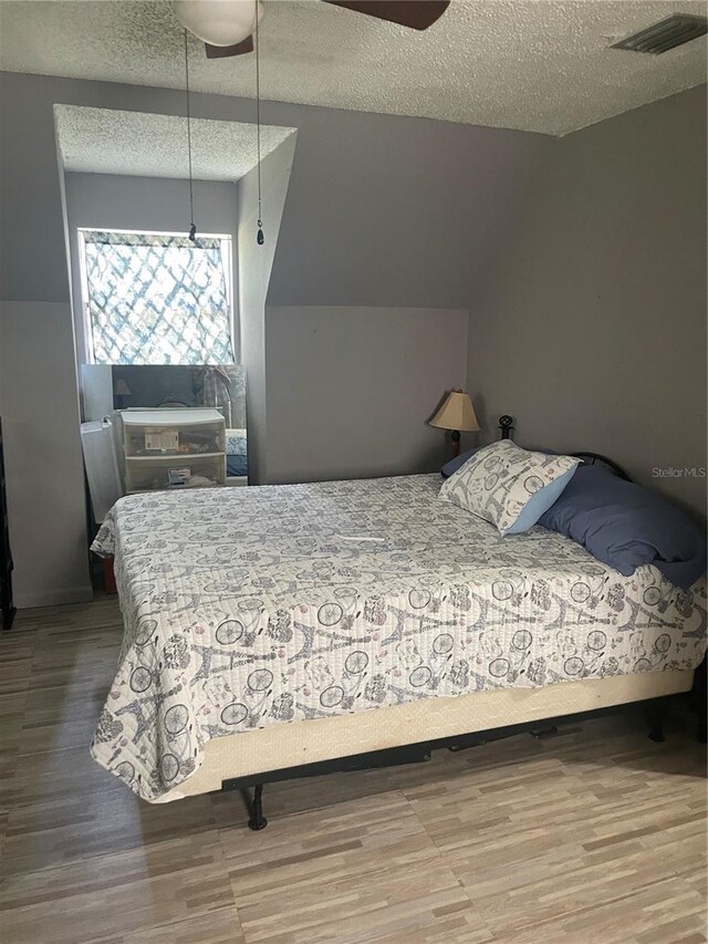 bedroom featuring ceiling fan, a textured ceiling, and wood-type flooring