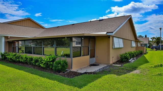 11 Andrea Dr, New Smyrna Beach, FL 32168 - back of house featuring a sunroom, a yard, and roof with shingles