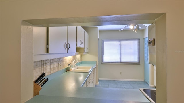 kitchen featuring white cabinets, backsplash, light tile patterned flooring, and sink