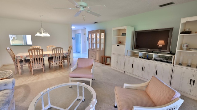 carpeted living room featuring ceiling fan with notable chandelier