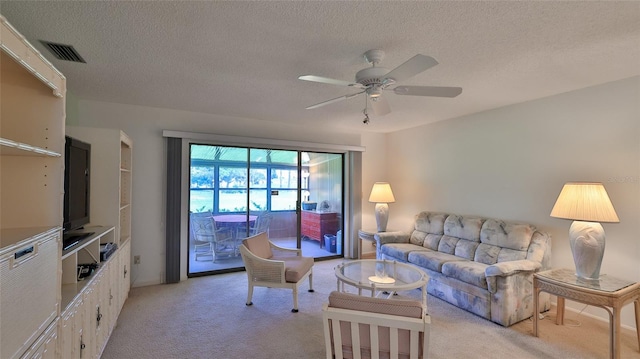 living room featuring ceiling fan, light colored carpet, and a textured ceiling