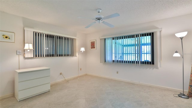 unfurnished room with ceiling fan and a textured ceiling