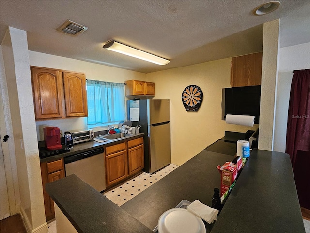 kitchen with a textured ceiling, sink, and stainless steel appliances