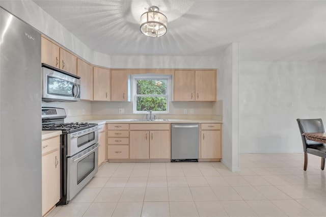 kitchen with sink, a chandelier, a textured ceiling, light brown cabinets, and appliances with stainless steel finishes