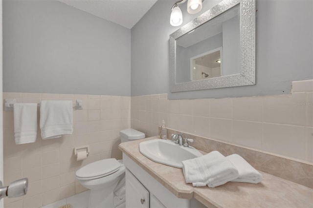 bathroom featuring vanity, toilet, and tile walls