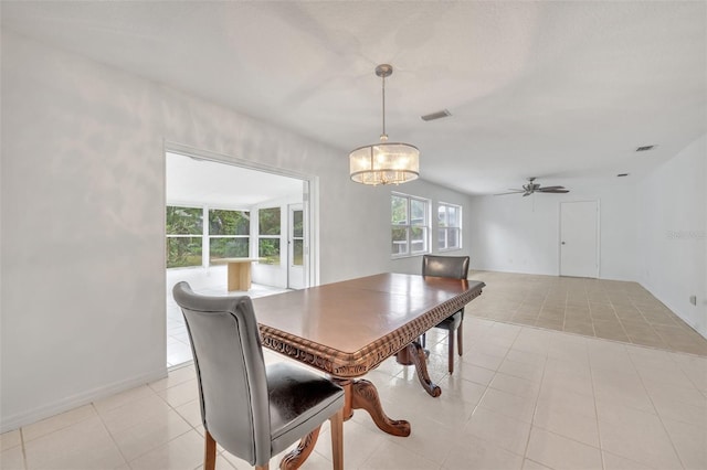 tiled dining area with ceiling fan with notable chandelier