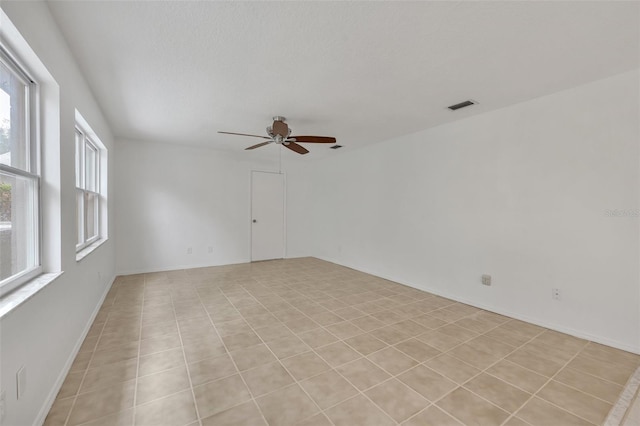 tiled spare room featuring ceiling fan