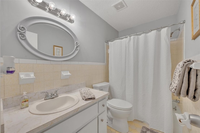 bathroom featuring toilet, tile patterned flooring, a textured ceiling, and tile walls