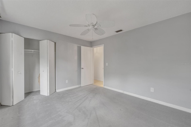 unfurnished bedroom featuring light carpet, ceiling fan, and a closet