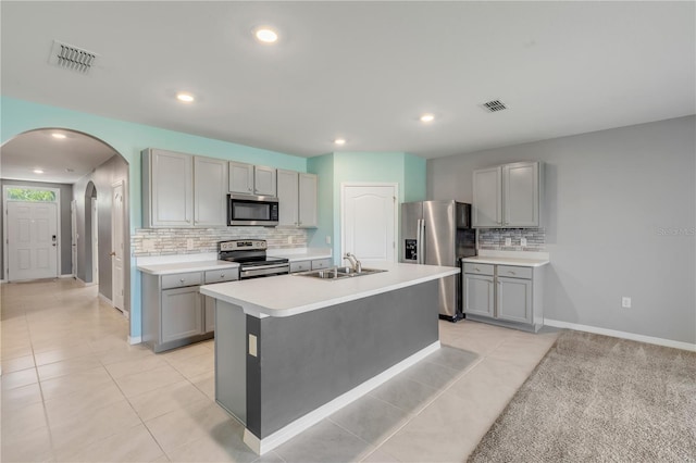 kitchen featuring gray cabinetry, a kitchen island with sink, sink, and stainless steel appliances