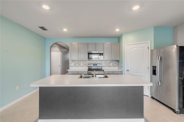 kitchen with a kitchen island with sink, stainless steel appliances, sink, and gray cabinetry