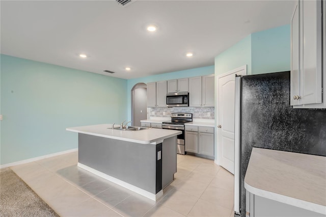 kitchen with a kitchen island with sink, stainless steel appliances, sink, gray cabinets, and light tile patterned floors