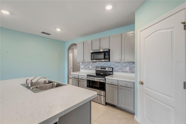 kitchen with stainless steel appliances, light tile patterned flooring, gray cabinets, and sink