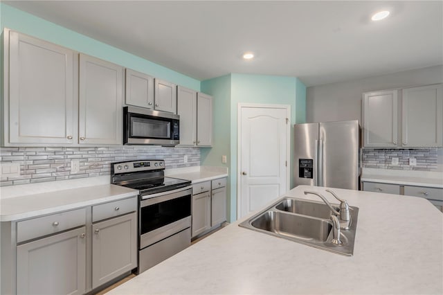 kitchen featuring gray cabinetry, decorative backsplash, sink, and stainless steel appliances