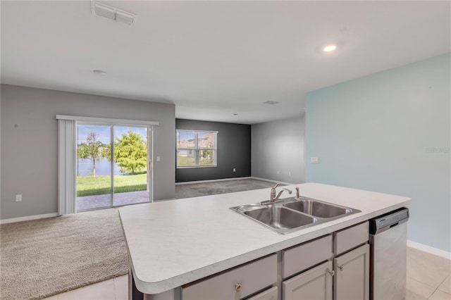 kitchen featuring an island with sink, sink, stainless steel dishwasher, and light tile patterned flooring