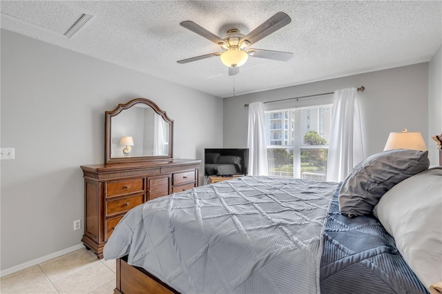 bedroom featuring light tile patterned flooring, ceiling fan, and a textured ceiling