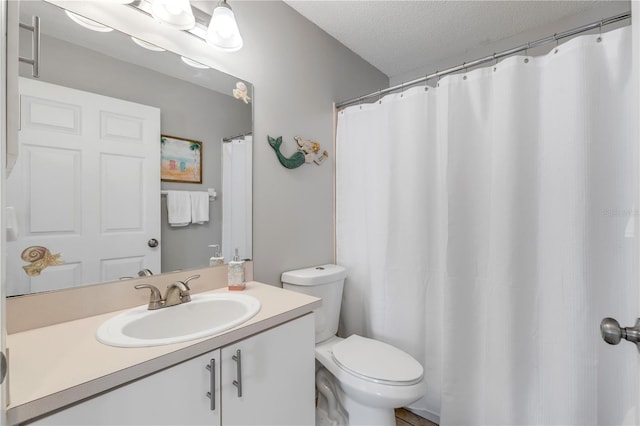 bathroom featuring a textured ceiling, vanity, and toilet