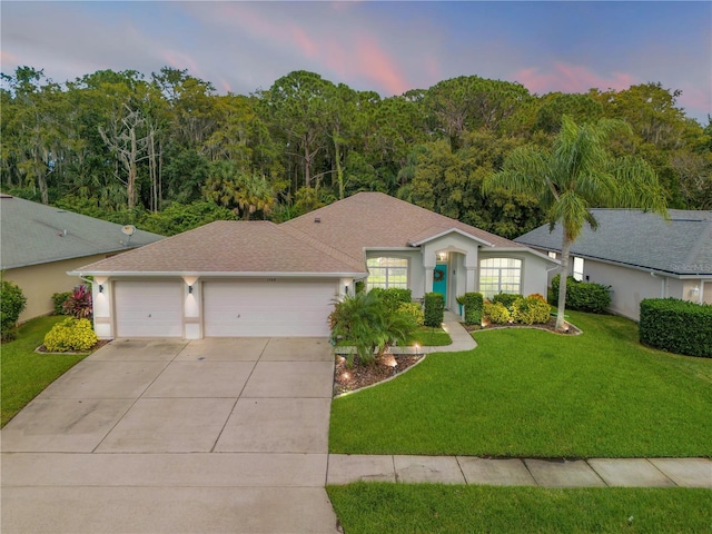 ranch-style home with a garage and a yard