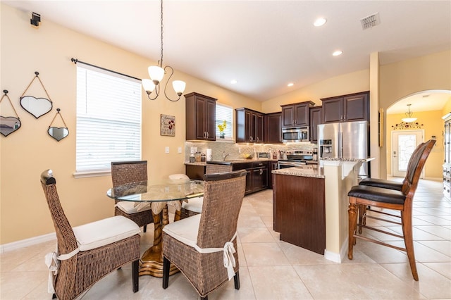 tiled dining space featuring lofted ceiling and a chandelier