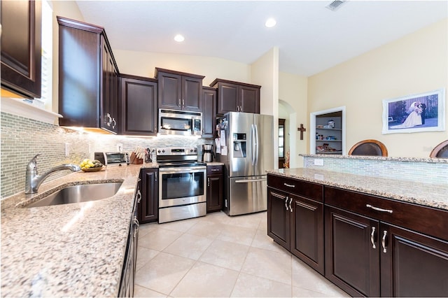 kitchen with backsplash, light stone counters, stainless steel appliances, sink, and light tile patterned floors