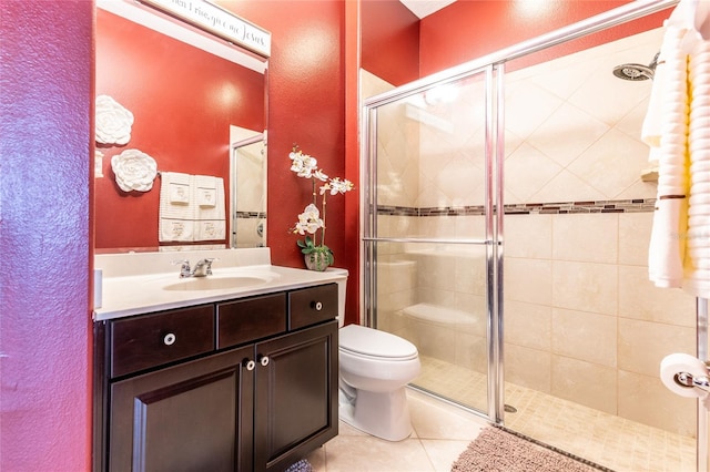 bathroom with tile patterned floors, vanity, a shower with shower door, and toilet