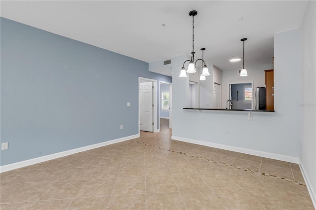 unfurnished living room featuring sink, a chandelier, and light tile patterned floors