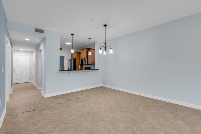 interior space with stainless steel appliances, a breakfast bar, kitchen peninsula, an inviting chandelier, and light tile patterned floors