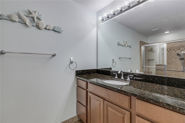 bathroom featuring a shower with shower door, vanity, and a textured ceiling